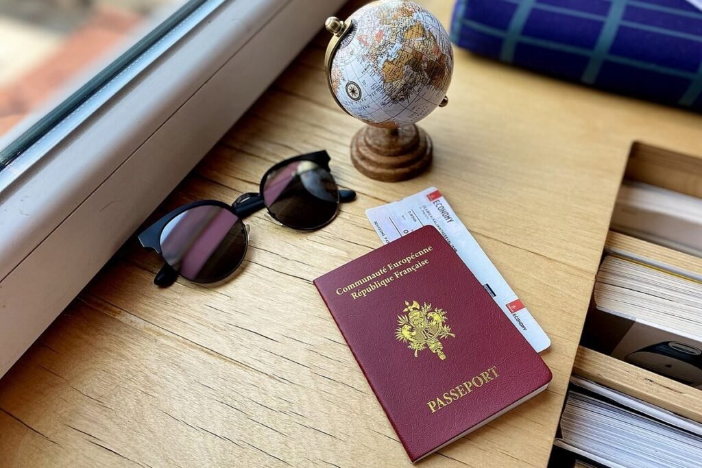 Passeport français posé sur une table en bois près de lunettes de soleil et d'un petit globe