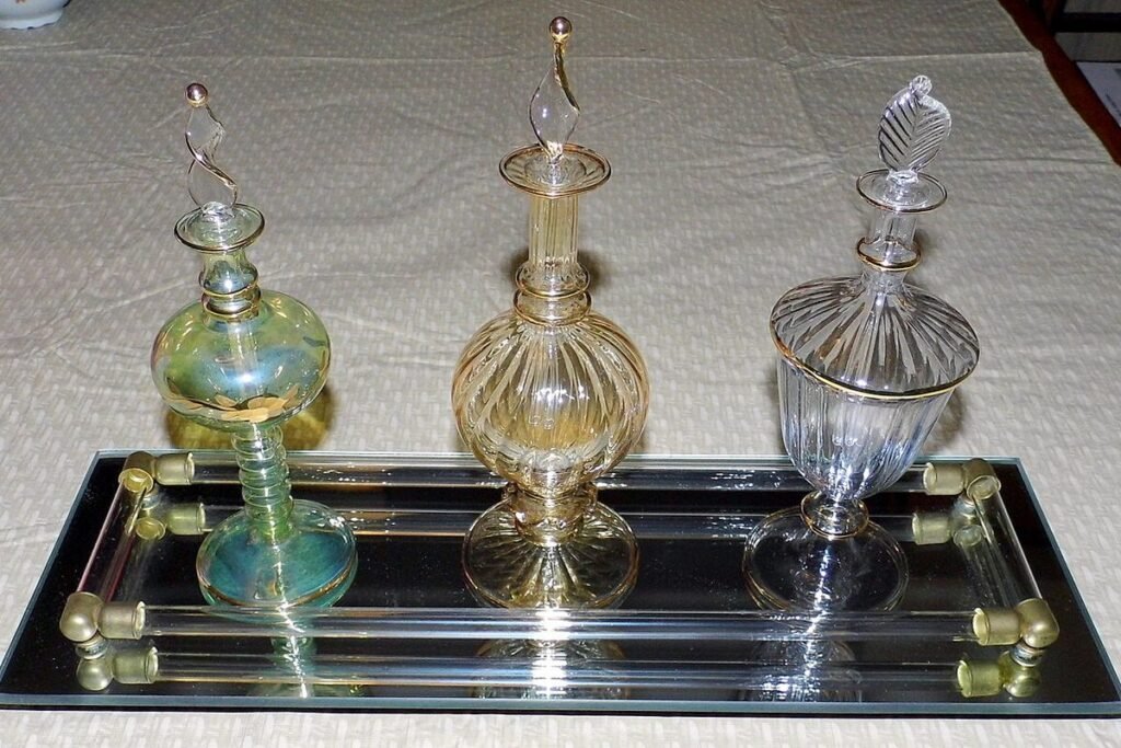 Trois flacons de parfum anciens en verre ouvragé sur un plateau à miroir