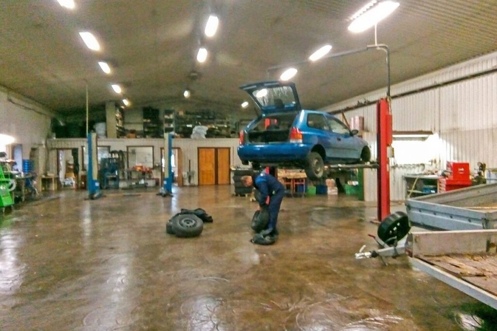 Atelier de garage avec une voiture levée sur un pont élévateur
