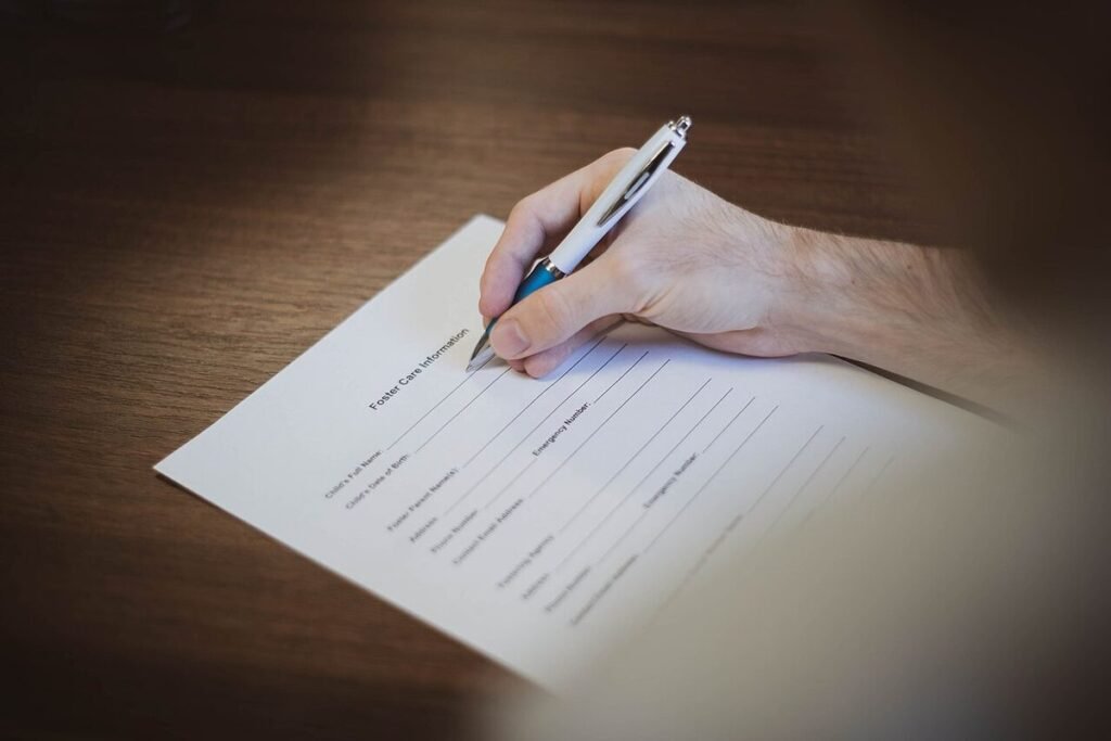 Main tenant un stylo et remplissant un formulaire papier sur une table