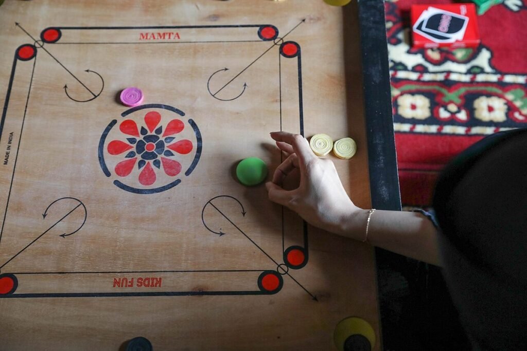Plateau de carrom en bois avec ses pions, une main prête à jouer