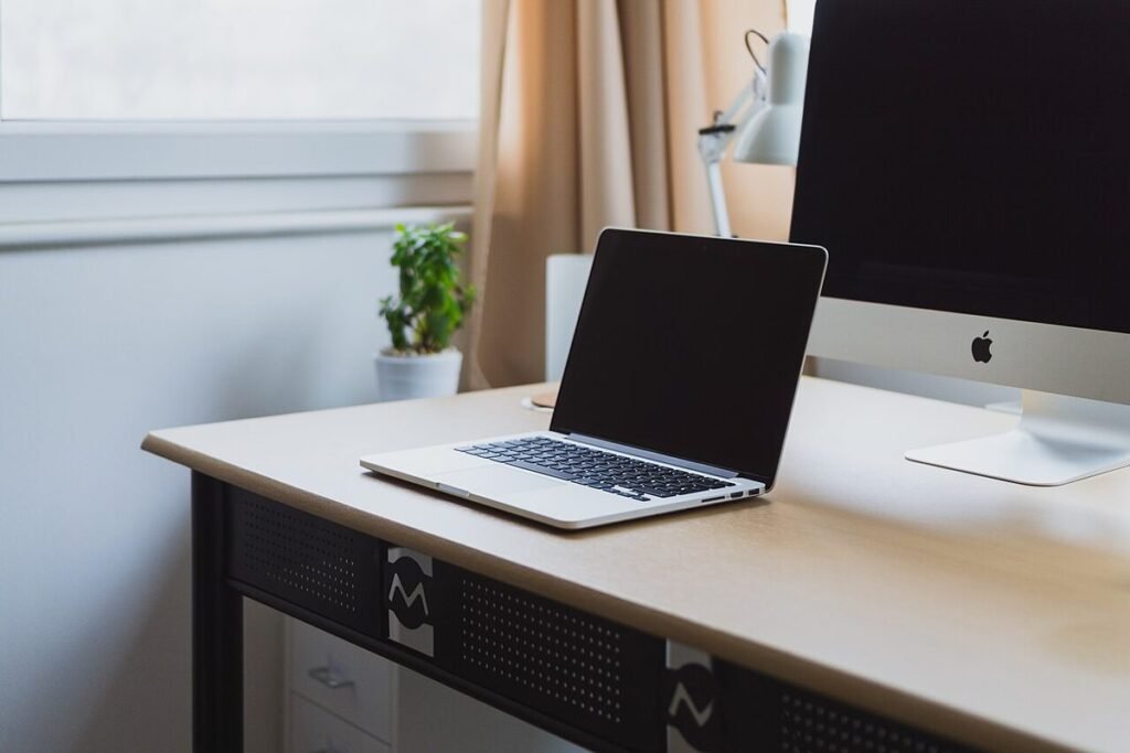 Bureau lumineux avec ordinateur portable et écran près d'une fenêtre