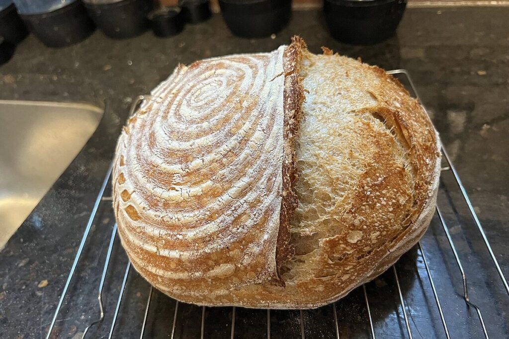 Miche de pain au levain grignée posée sur une grille de refroidissement