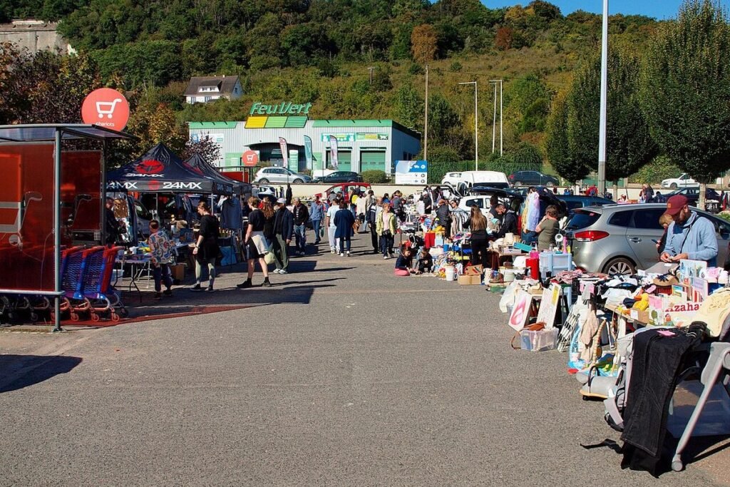 Allée d'un vide-grenier en plein air bordée de stands et de chineurs