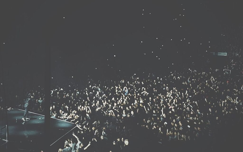 Salle de concert comble vue depuis les gradins, public massé devant la scène